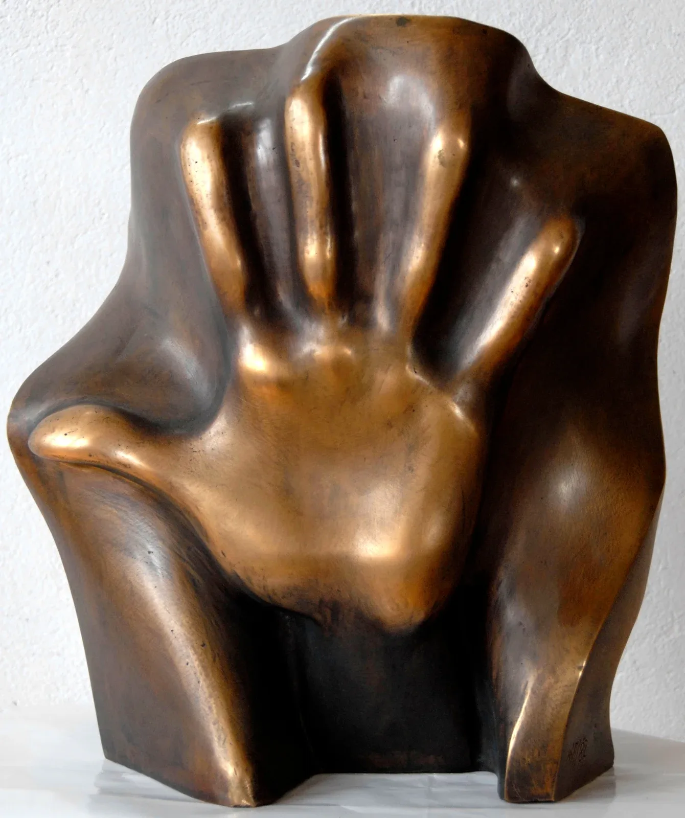 Pamięci Emila B.: bronzo dalla patina calda in cui un palmo aperto, con le cinque dita distese, emerge in rilievo da una massa chiusa e irregolare