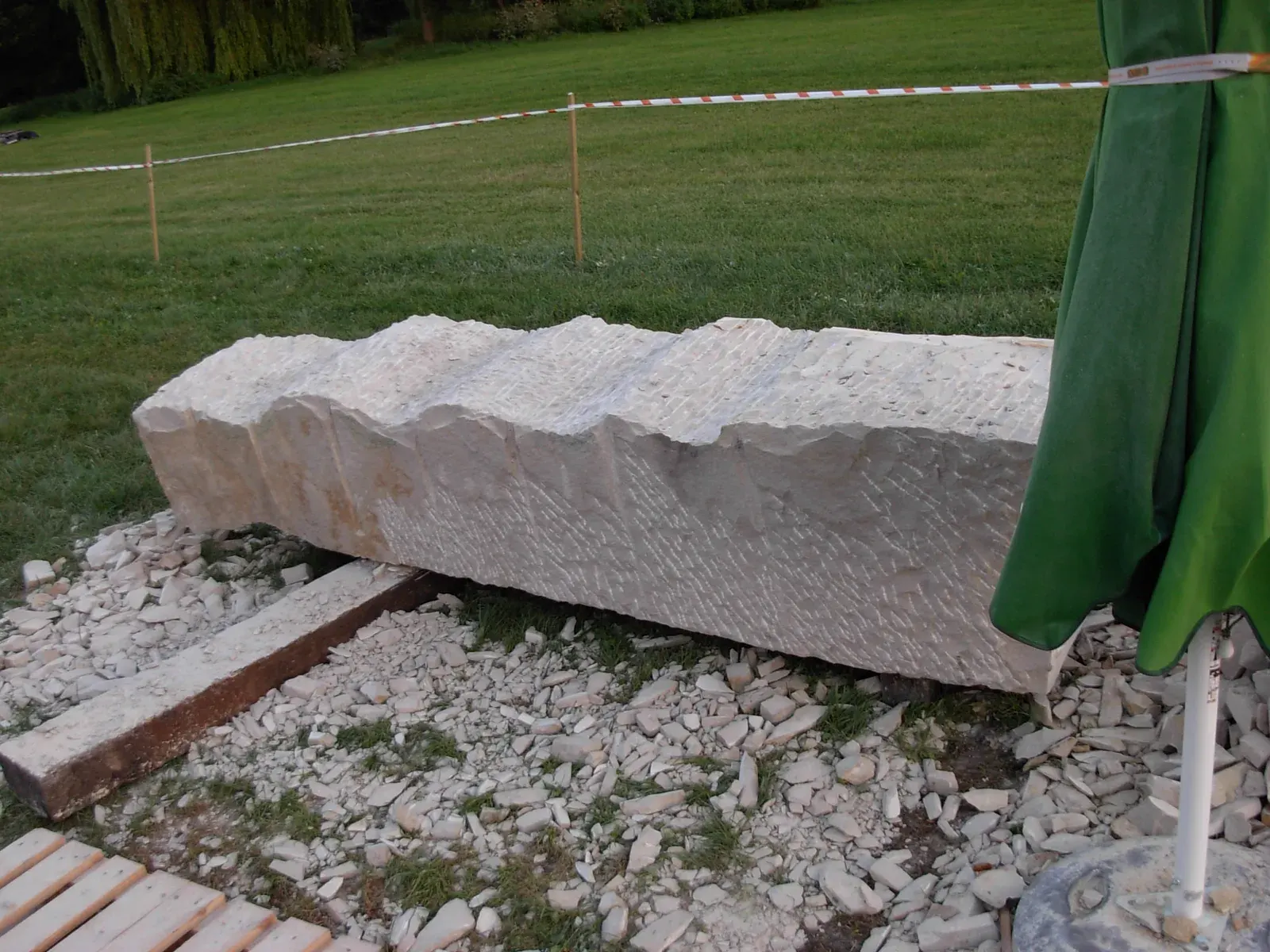 Etiuda — Il blocco disteso sui pallet, con il profilo a onde già tagliato lungo il lato lungo; sullo sfondo il nastro del cantiere.