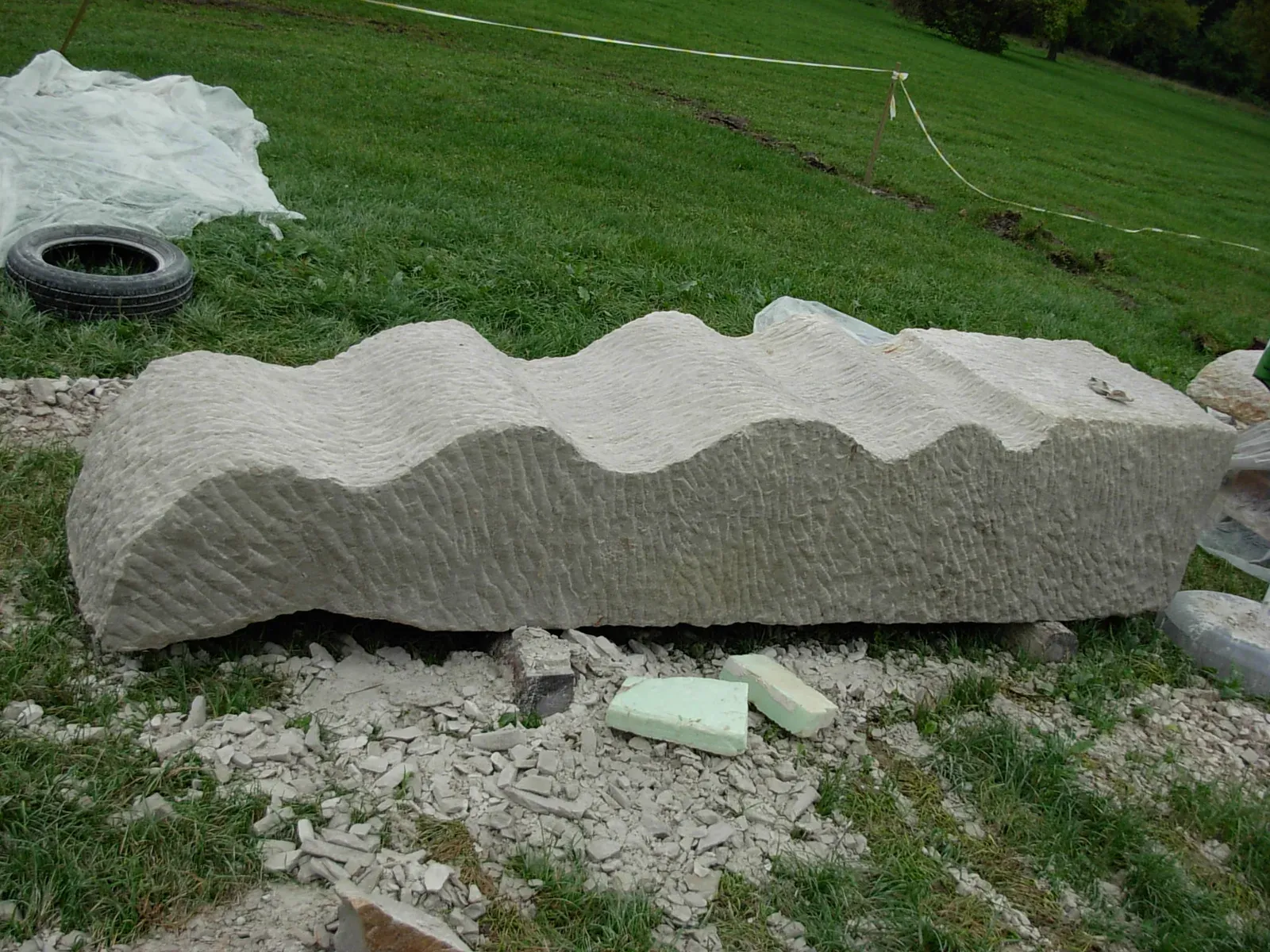 Il blocco finito, disteso sull’erba, con la superficie lavorata a punta fitta e il bordo a onde nettamente tagliato